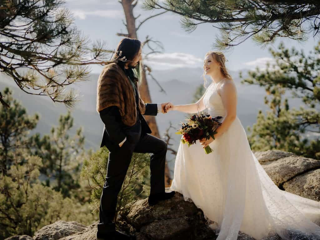 A bride and groom look at each other as they stand on a rock in front of mountain views at location very nearby sunrise amphitheater in Boulder colorado