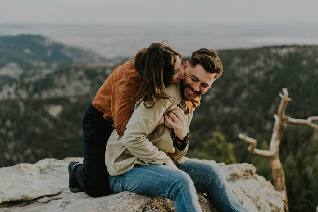 a couple kiss each other on the edge of lost gulch overlook at sunrise