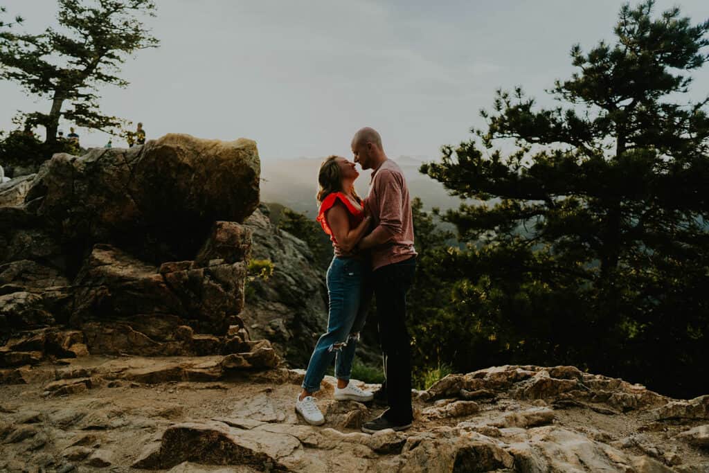 a couple looks at each other lovingly at sunset on the edge of lost gulch overlook for their boulder engagment photos by Alex medvick
