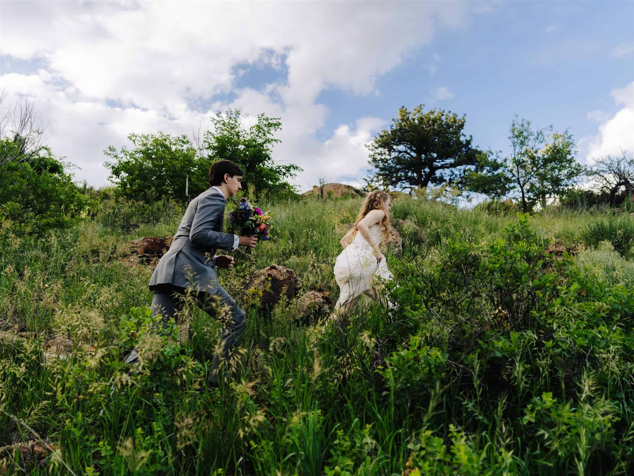 a bride and groom hike up a hill at their wedding hosted at Riverbend Lyons in Lyons colorado photographed by colorado wedding photographer Alex Medvick
