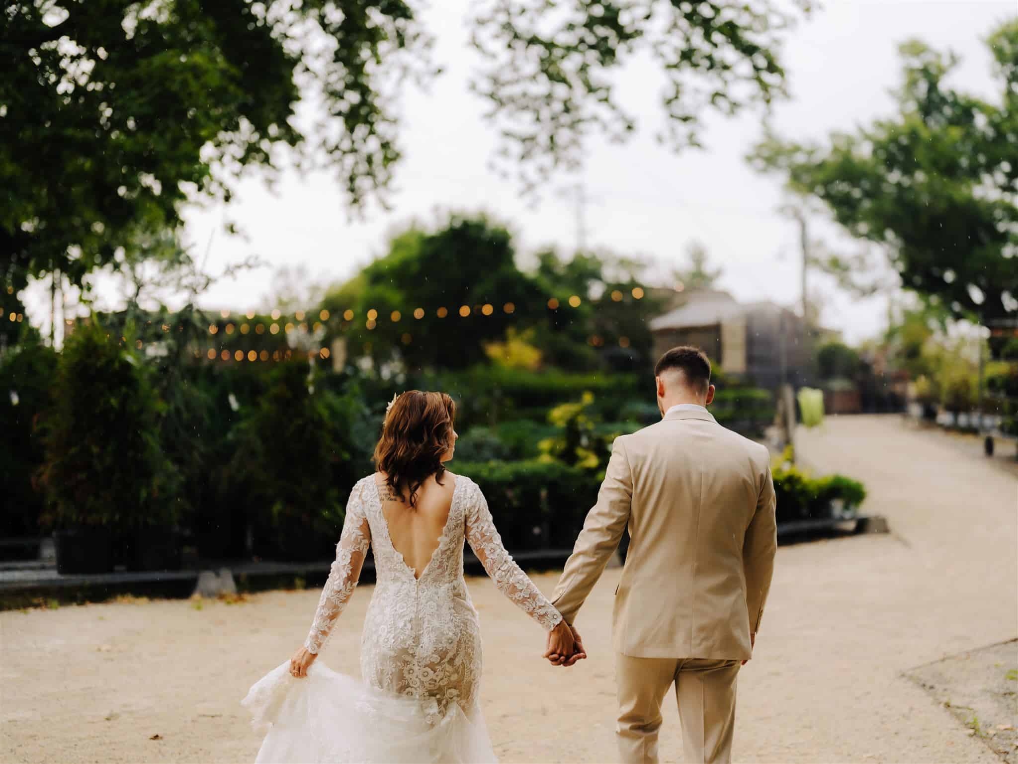 bride and groom walking holding hands with rain drops around them