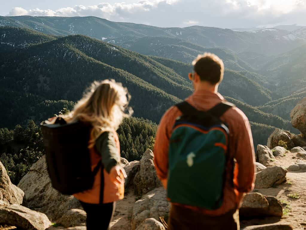 Couple with hiking backpacks viewing mountain vista near Lost Gulch Overlook Boulder Colorado elopement location