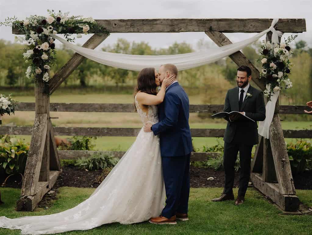 bride in a white dress and groom in a blue suit share a first kiss at durham hill farm