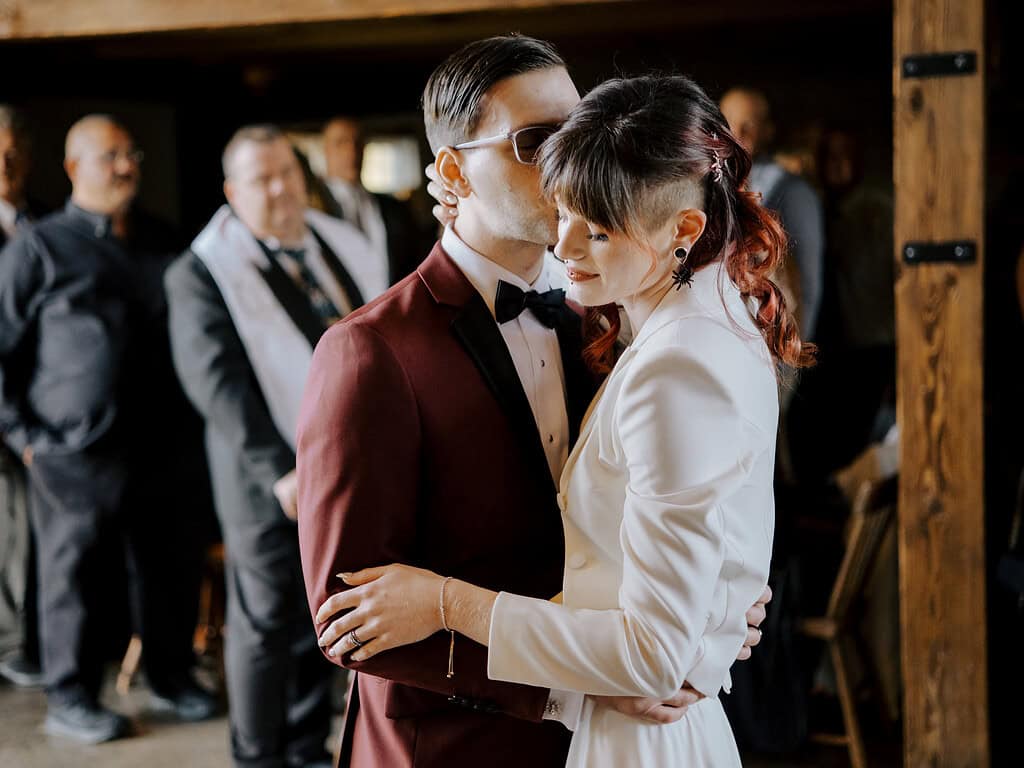 Bride in a white jacket and pink hair dances with groom in red suit at durham hill farm in pipersville PA